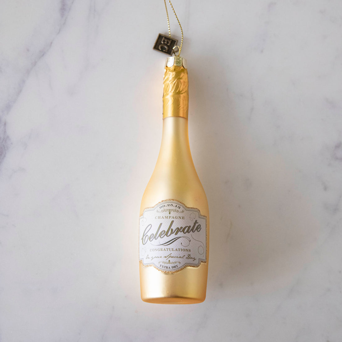 Congratulations Gold Champagne Ornament laying on a marble table.