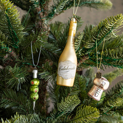 Three Olives Please Ornament, Champagne Ornament and Cheers Cork Ornament hanging on a tree. 