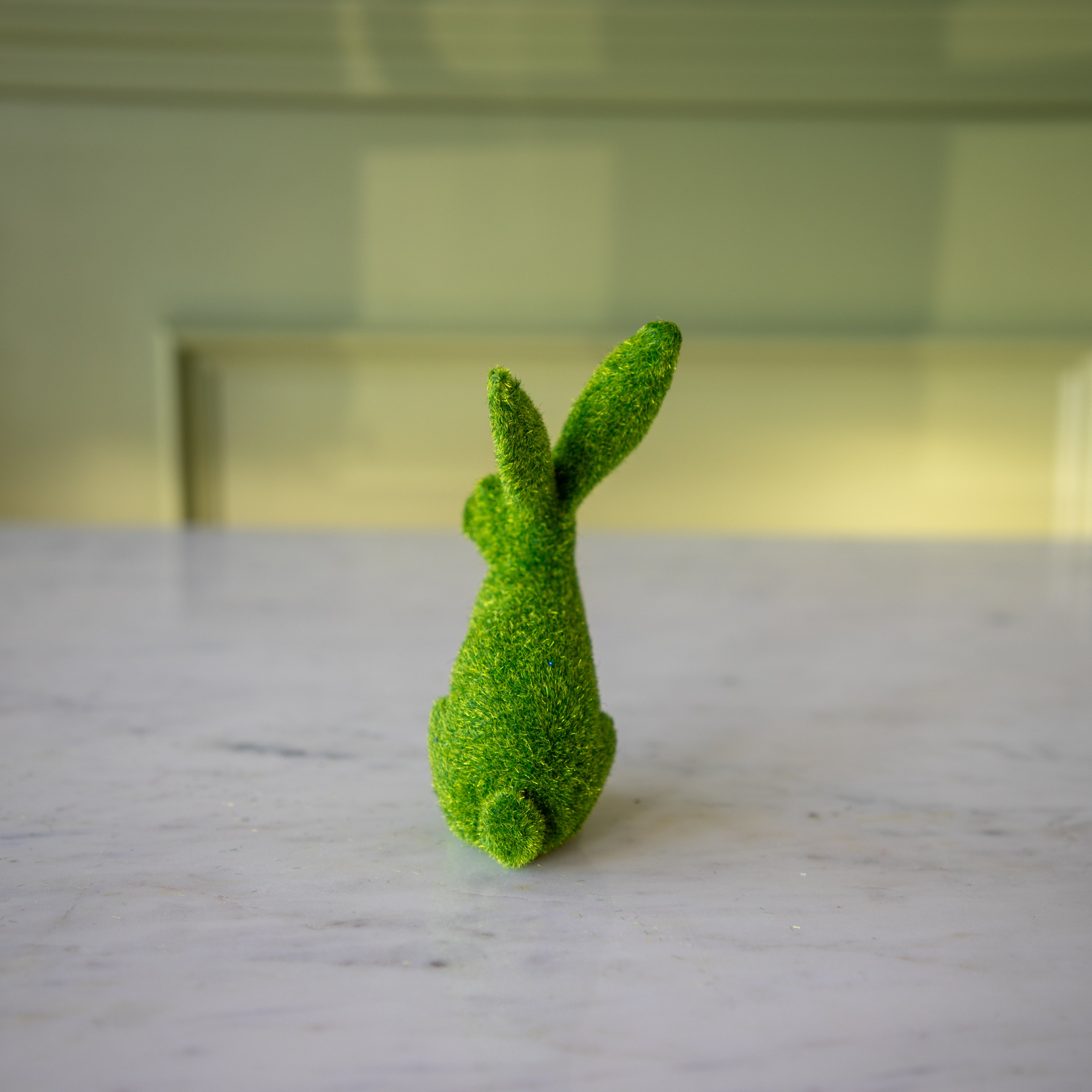 The back view of the large green flocked bunny with its ears back.