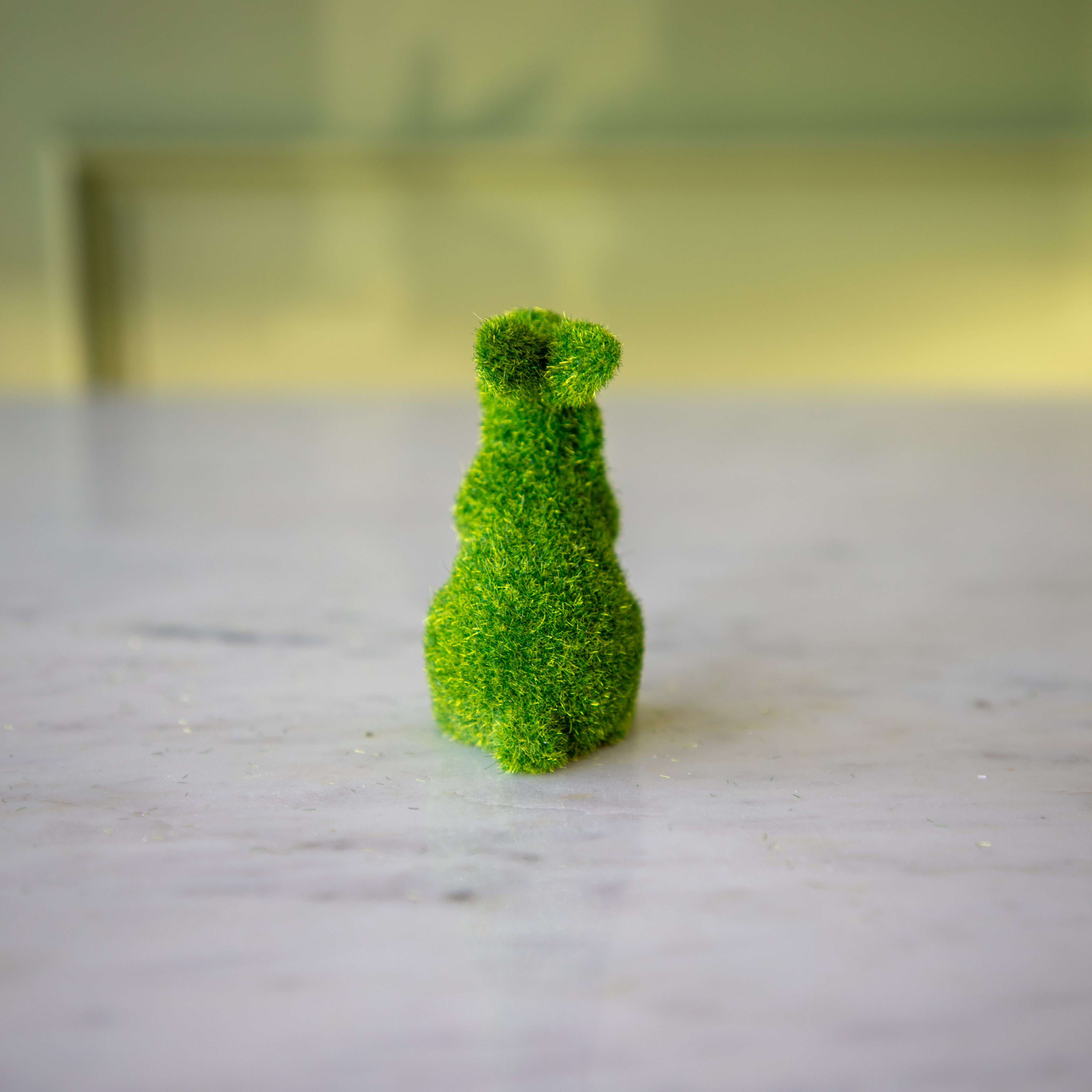 The back view of the extra small green flocked bunny on its hind legs and ears all the way back.