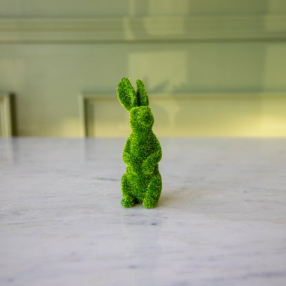 The front view of the medium green flocked bunny on its hind legs looking to the side.