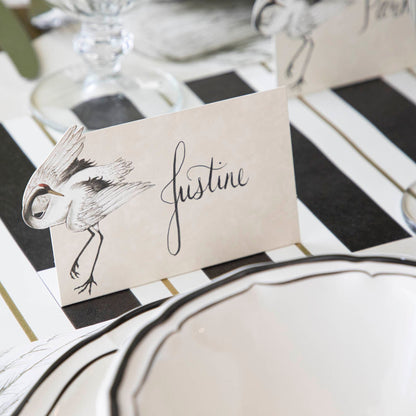 Crane Place Card with &quot;Justine&quot; written on it, behind an elegantly styled place setting for one.