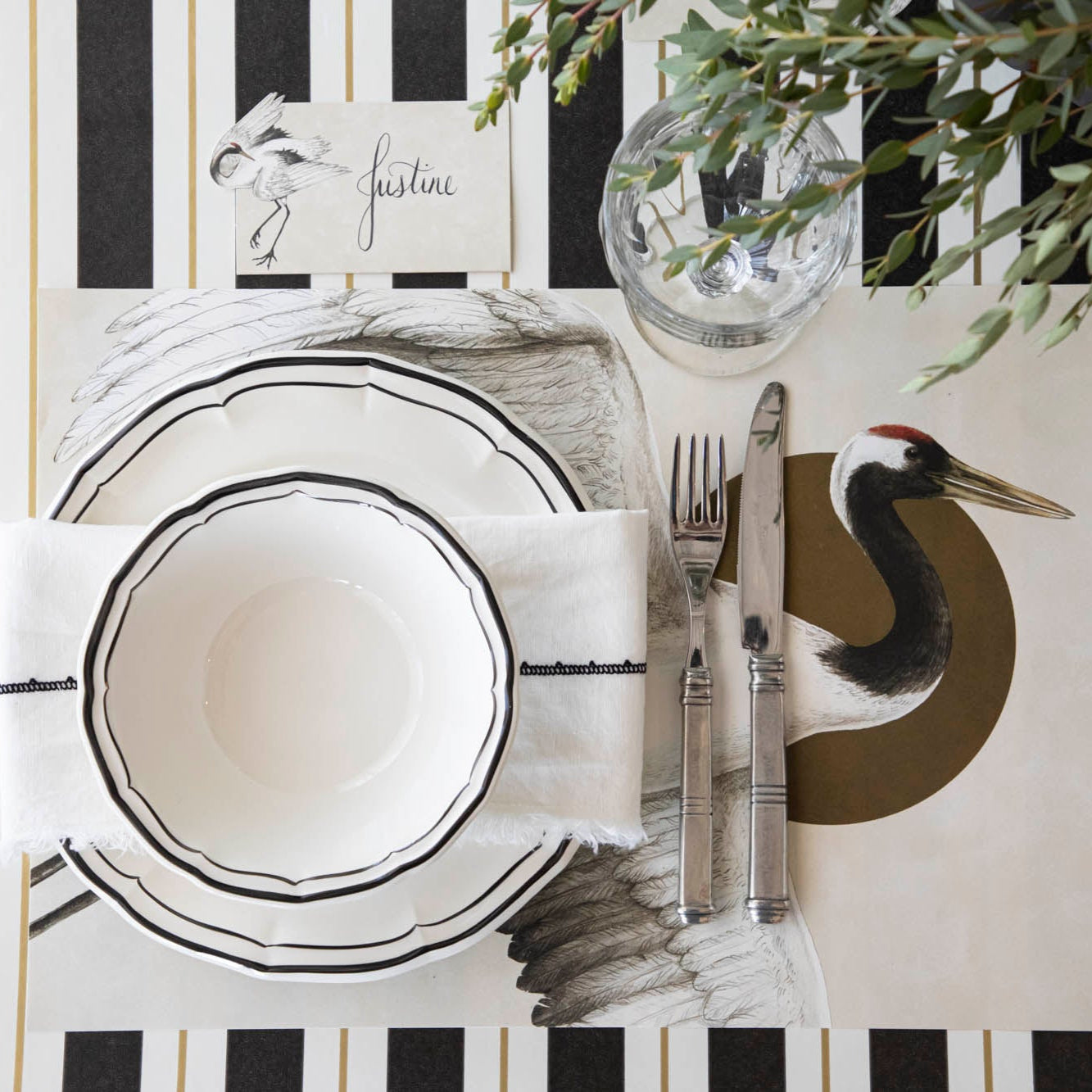 Crane Place Card with &quot;Justine&quot; written on it, behind an elegantly styled place setting for one.