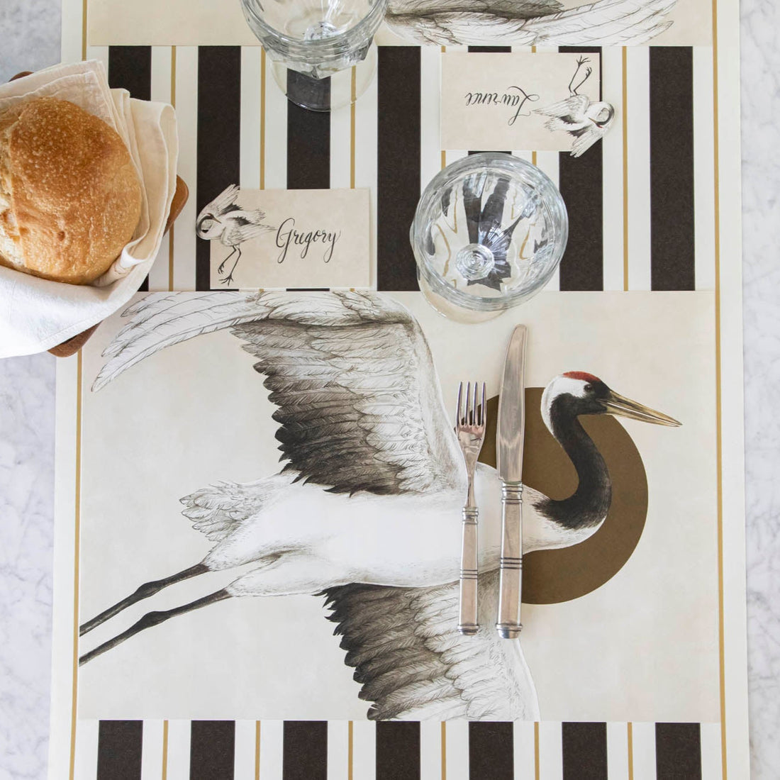 Eastern Crane Placemat on top of the Black &amp; Gold Awning Stripe Runner, on an elegantly styled table.