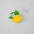 A Hester & Cook Lemon Enamel Pin adorned with leaves.