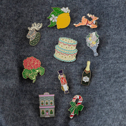 An Hester &amp; Cook enamel pin depicting a garden trophy with flowers in a vase, perfect for decorating a backpack.