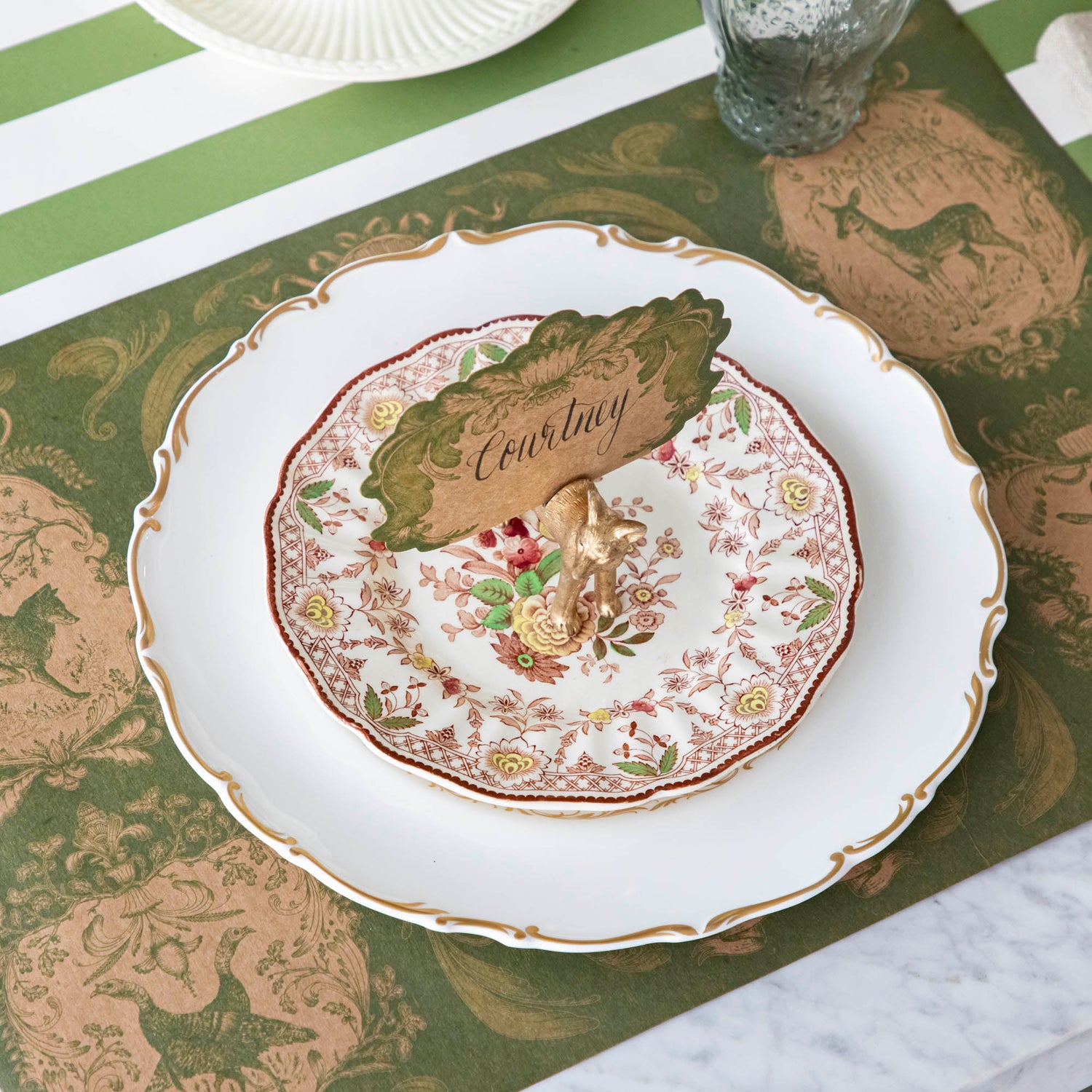 The Fox Name Card holder holding the Moss Fable Toile Place Card with &quot;Courtney&quot; written in cursive, held by a slot in the Fox&