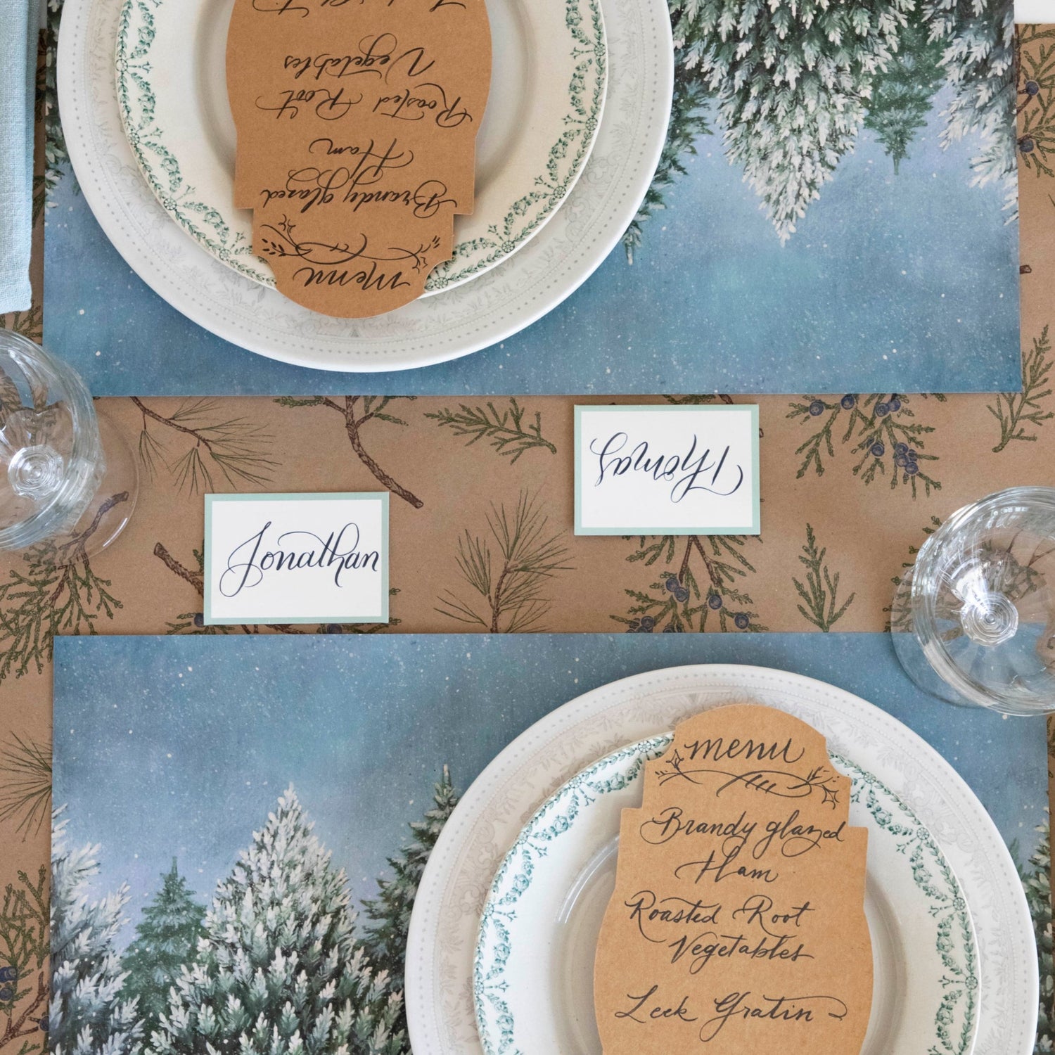 Close-up of the Juniper Sprigs on Kraft Runner under an elegant winter-themed table setting, from above.