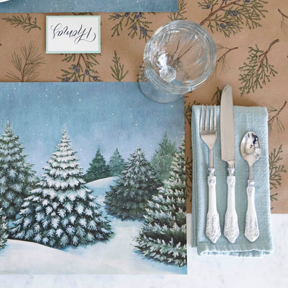 Evergreen Forest Placemat with silverware on top of a napkin, an empty glass and a Juniper Sprigs runner underneath. 