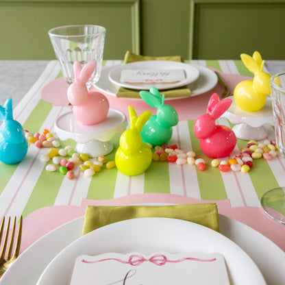 Six Bunny Candles assorted colors styled in the center of two spring place settings.