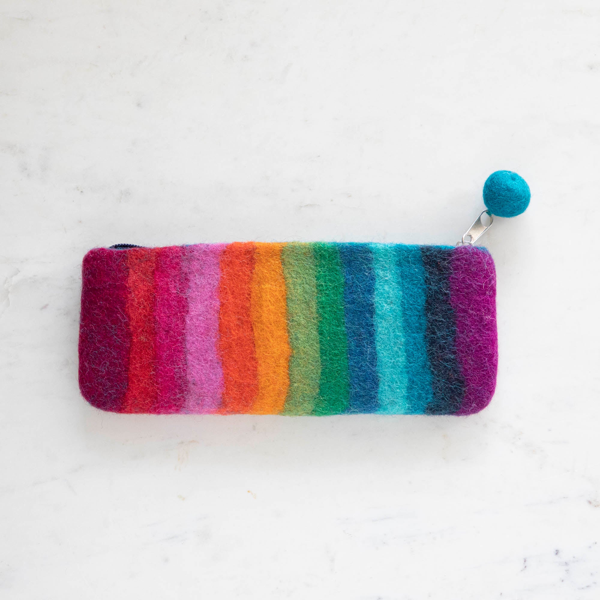 A Felt Rainbow Pencil Pouch with a felt pom on the end of the zipper pull.