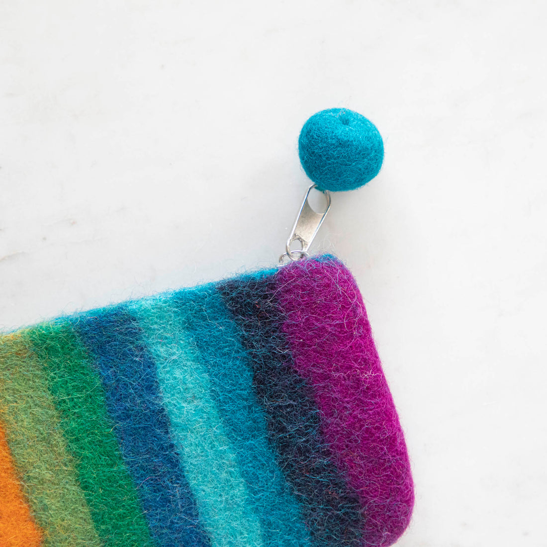 A close up of the Felt Rainbow Pouch with the felt pom at the end of the zipper pull.