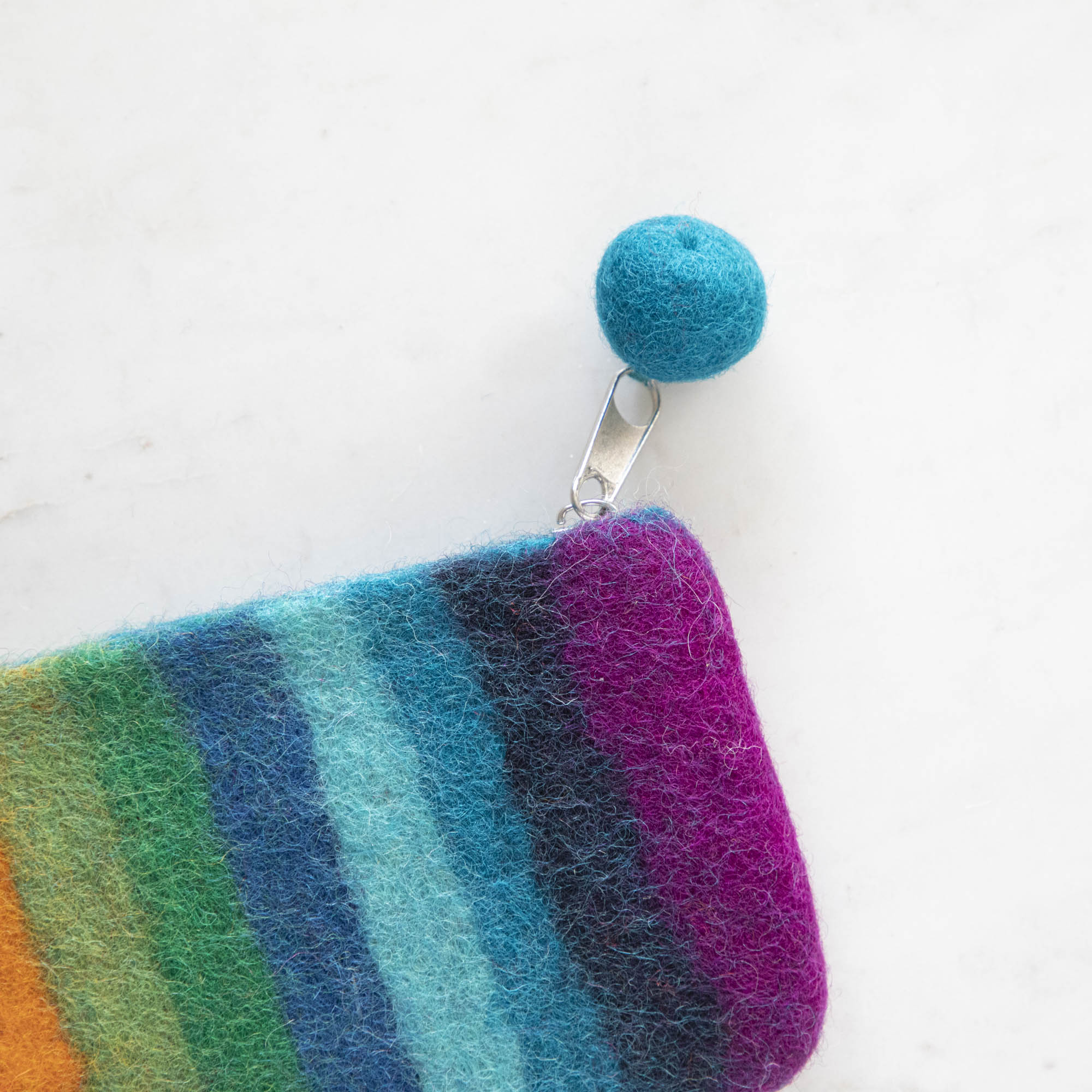 A close up of the Felt Rainbow Pouch with the felt pom at the end of the zipper pull.