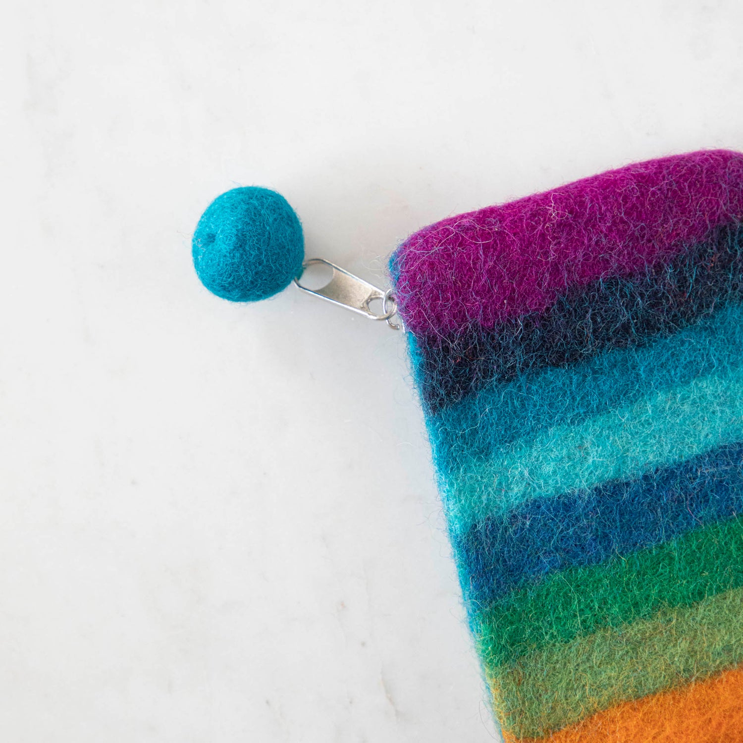 A close up of the Felt Rainbow Pouch with the felt pom at the end of the zipper pull.