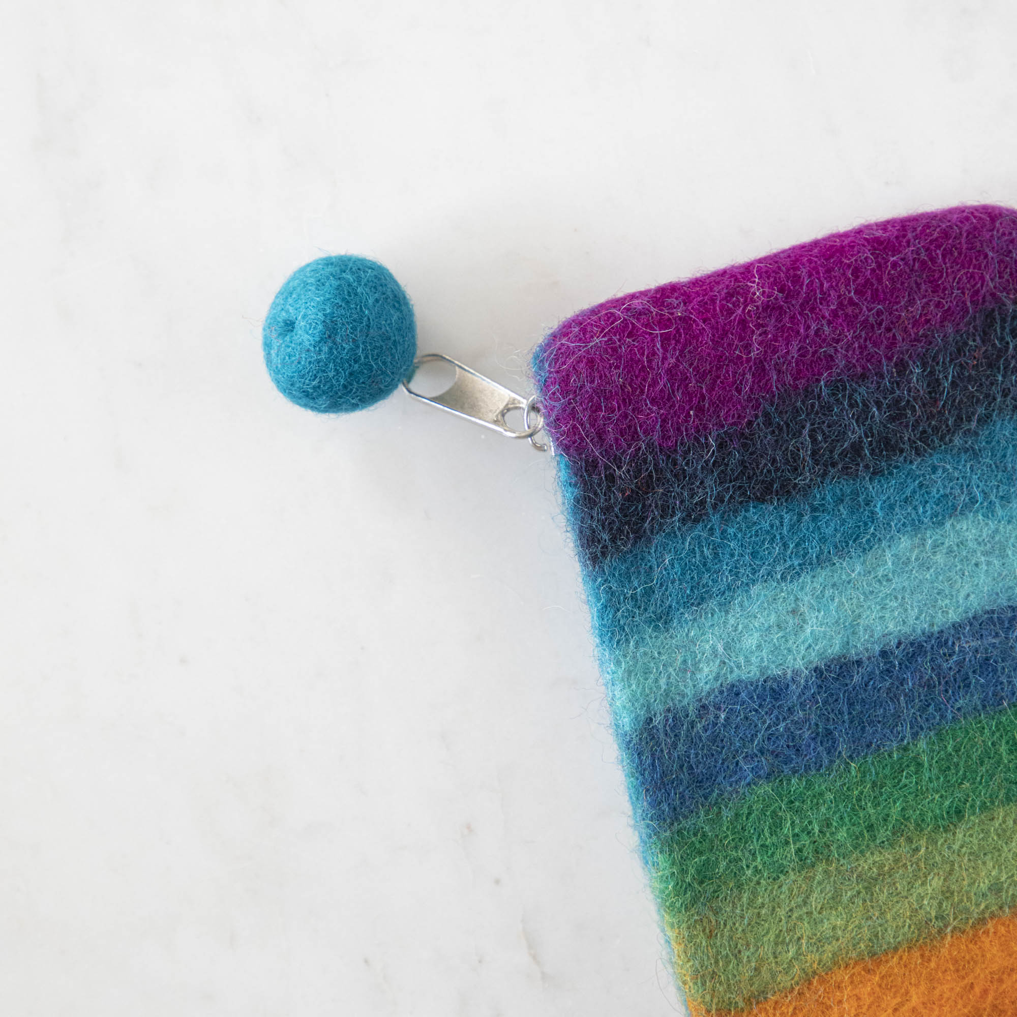 A close up of the Felt Rainbow Pouch with the felt pom at the end of the zipper pull.