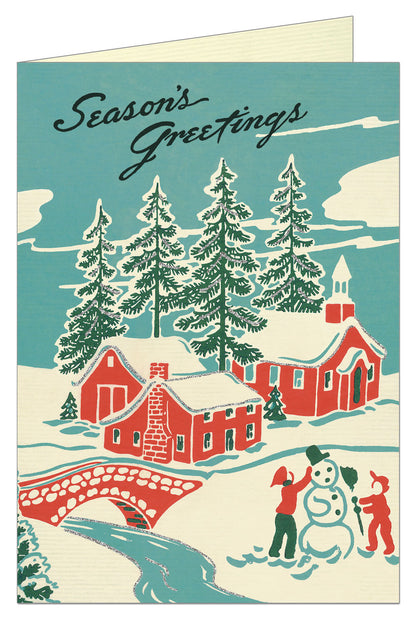 Front of card showing rural scene with children making a snowman and red home and church with trees in background. 