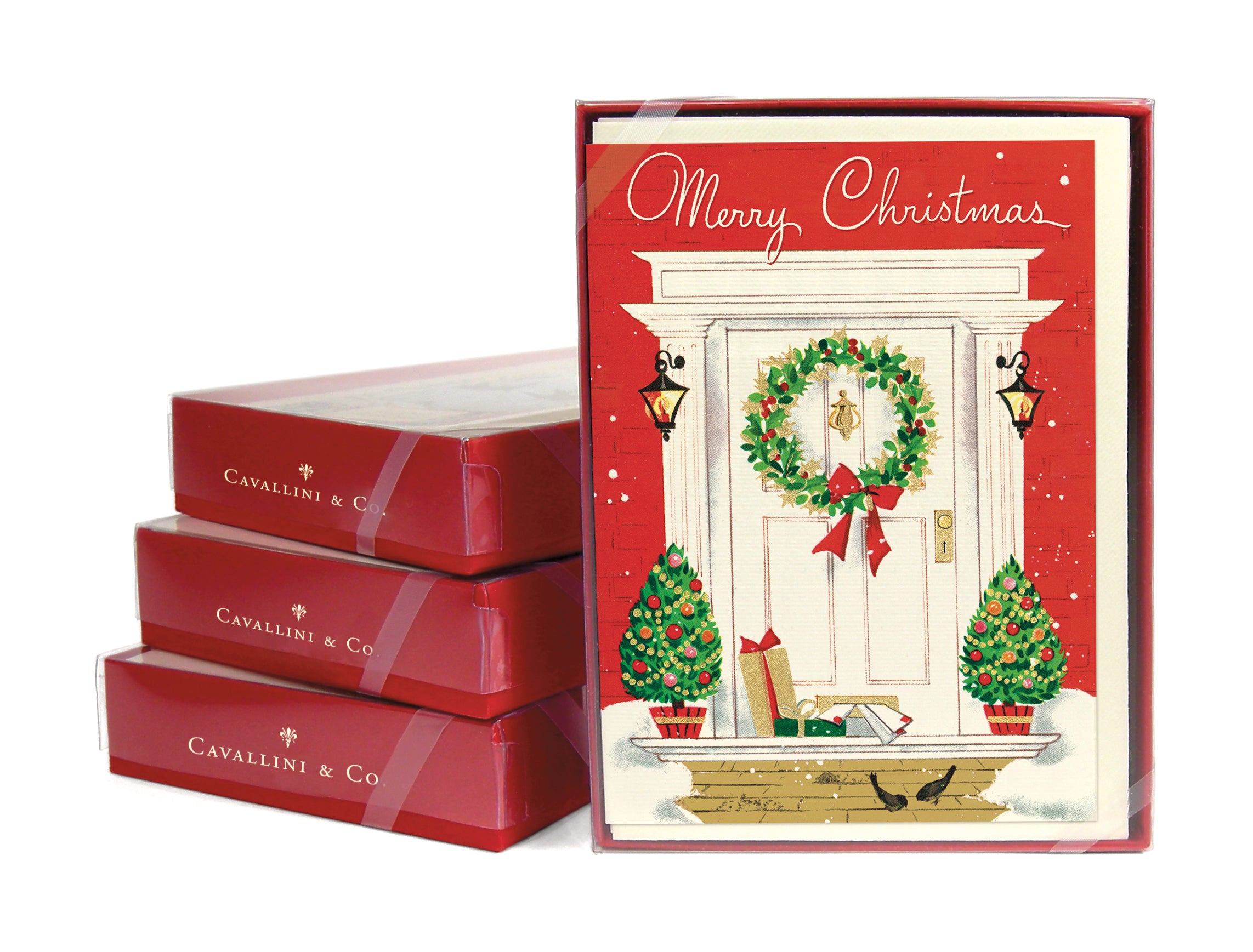 Three stacked boxed card sets next to a front facing boxed card set of the Merry Christmas Home Card showing a front porch decorated for the holidays.