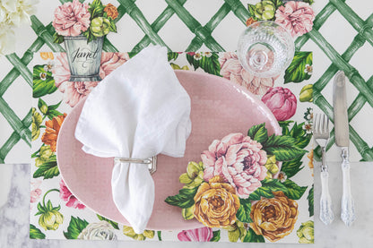 Top-down view of an elegant floral place setting featuring a Garden Derby Place Card labeled &quot;Janet&quot; laying flat on the table next to the plate.