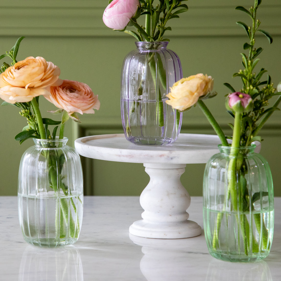 Lilac, green and clear Glass Bud Vases with spring flowers in them.