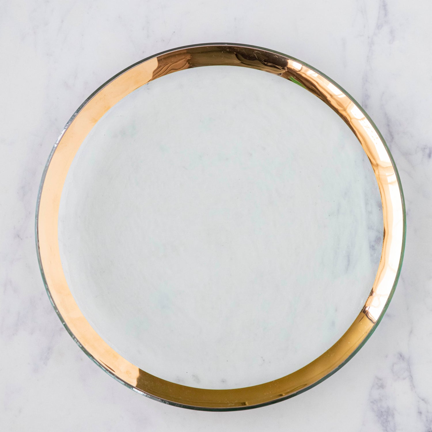 Annie Glass Roman Antique Dinner Plate, adorned with a 24-karat gold band, on a marble table.