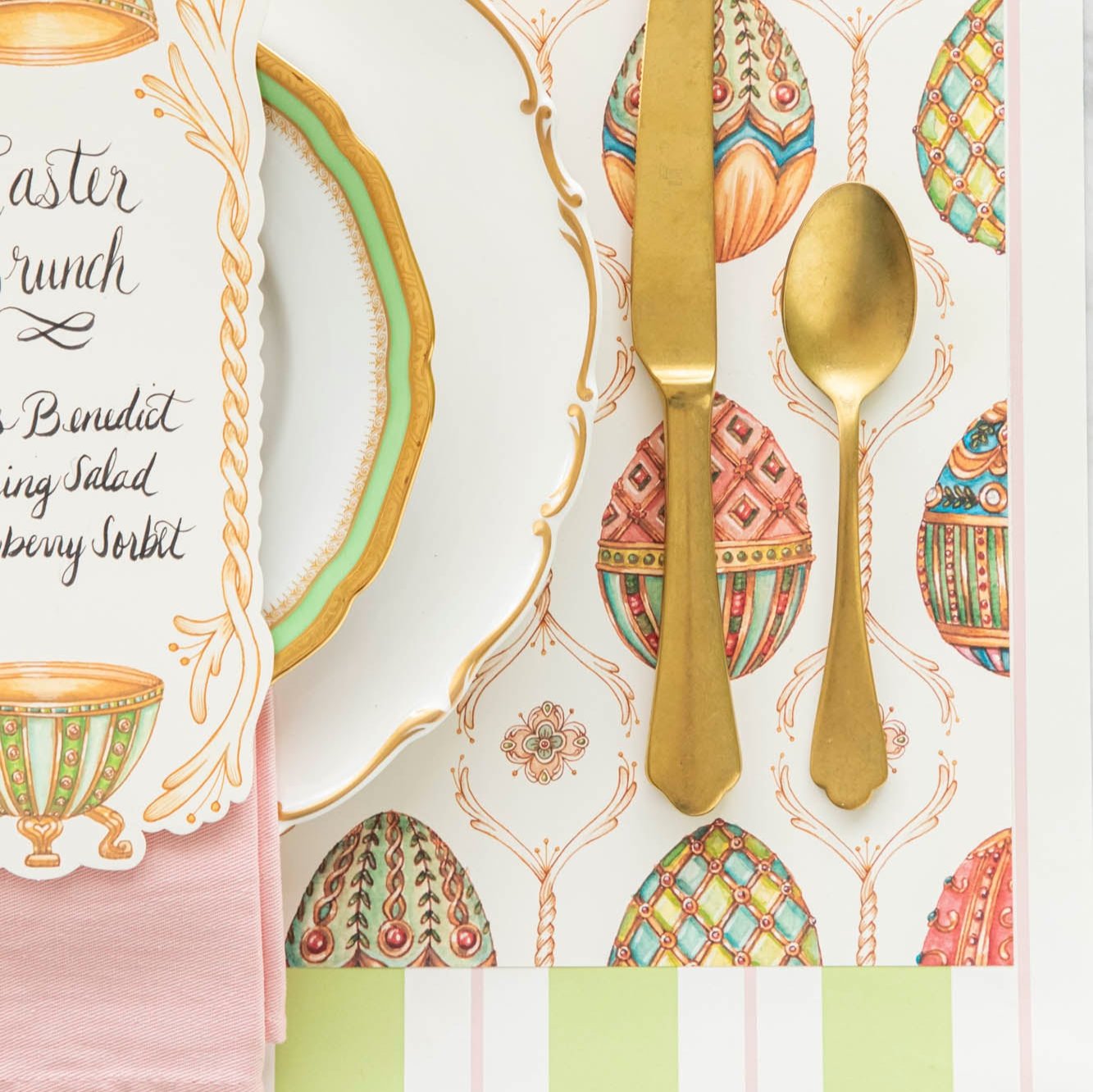 A close up of the Exquisite Egg Hunt Placemat with gold silverware and dinnerware on top.