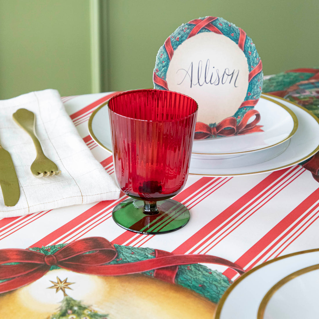 Green &amp; red stemmed flute glass on a Christmas themed table setting.