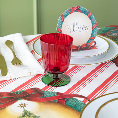 Green &amp; red stemmed flute glass on a Christmas themed table setting.