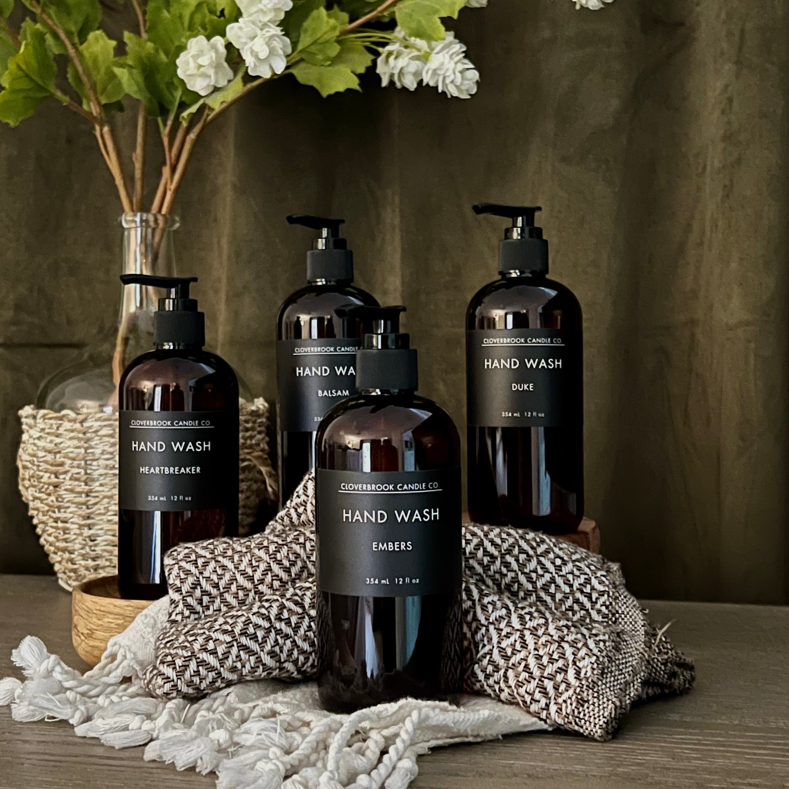 Cloverbrook Candle Co., various bottles of hand wash, styled near a plant with blankets.