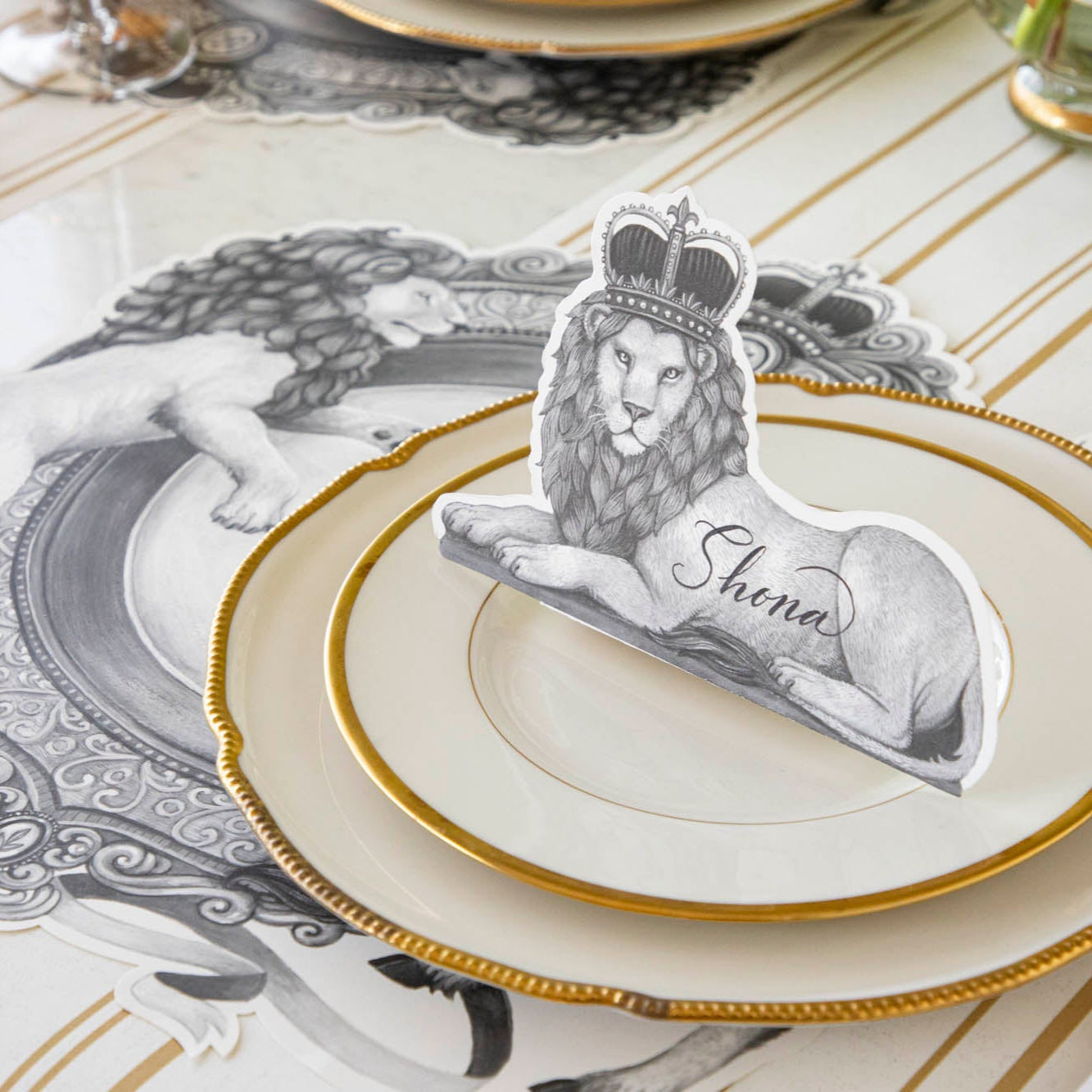 Regal Lion Place Card with &quot;Shona&quot; written on it, sitting upwards on dinner plates.