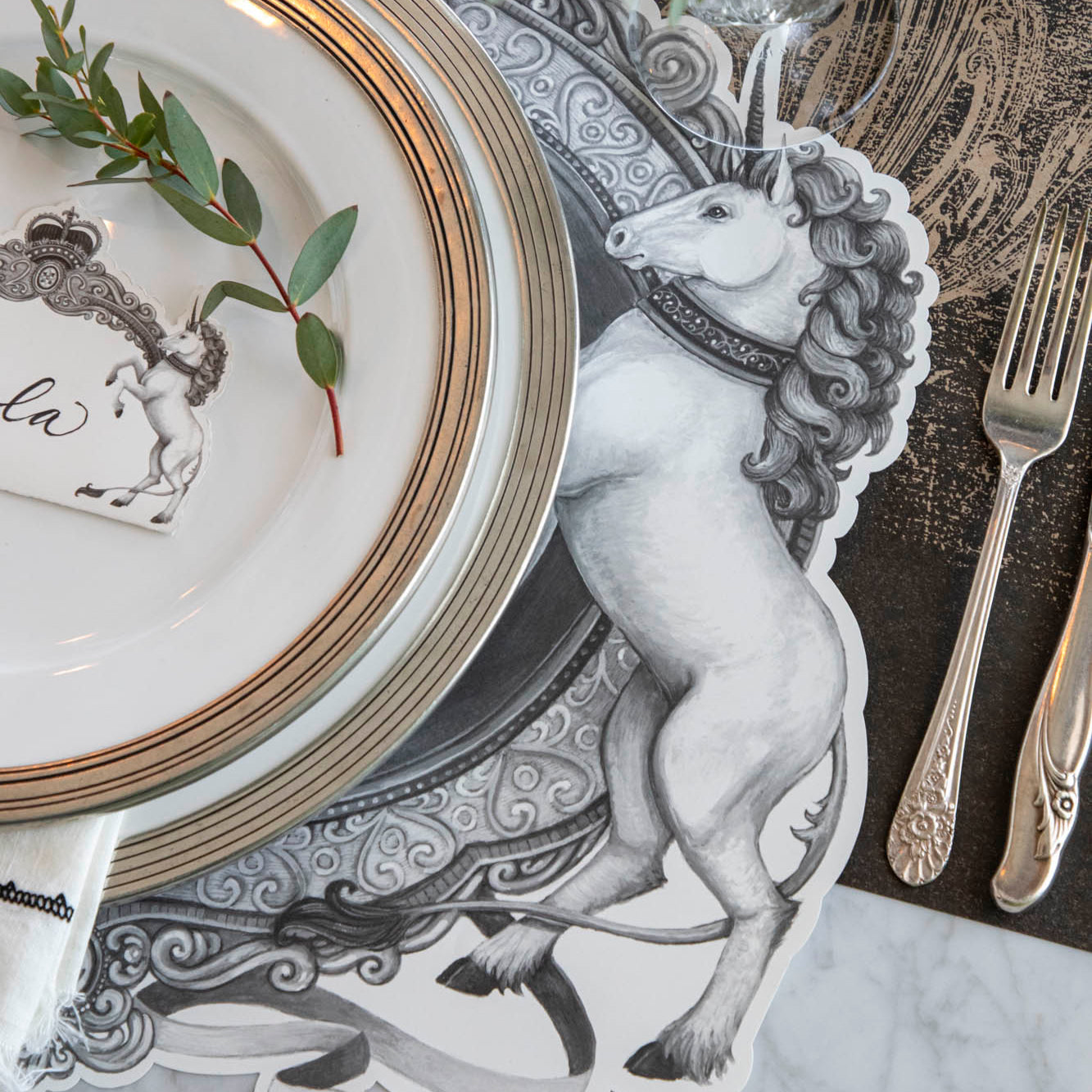 Die-cut H&amp;C Regal Crest Placemat on the Black Archival Runner, with the unicorn showing from under the dinner plates.