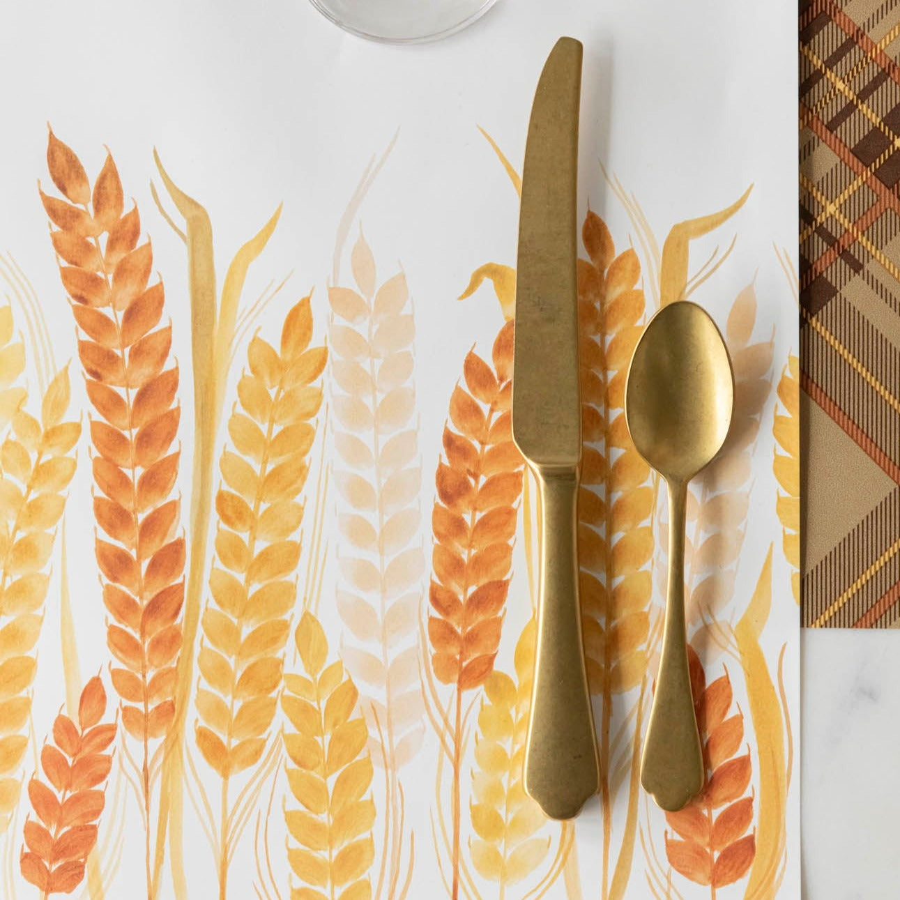 Close-up of the Golden Wheat Placemat under gold flatware in a fall themed place setting.