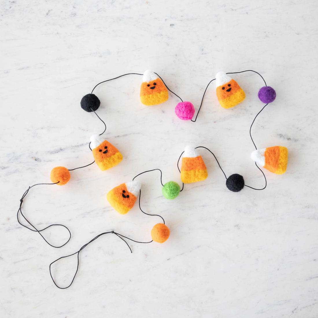 Wool halloween candy corn garland featuring smiley face candy corn pieces and colorful balls. 