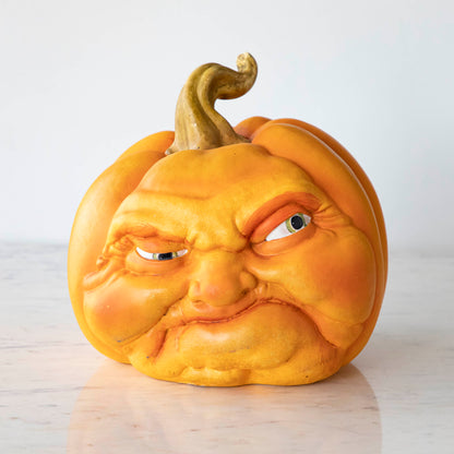 A scowling resin pumpkin on a marble table.