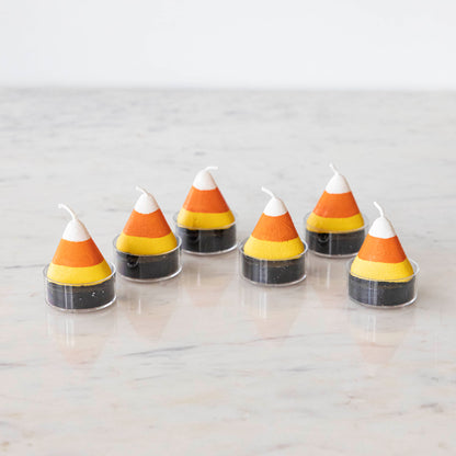 Candy corn themed tea light candles on a marble table.