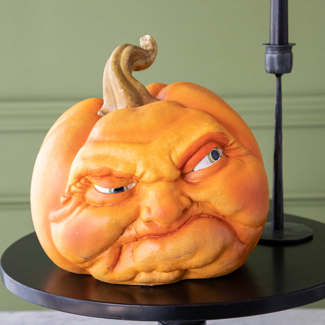 A close-up view of a pumpkin making a mean face on top of a black stand.