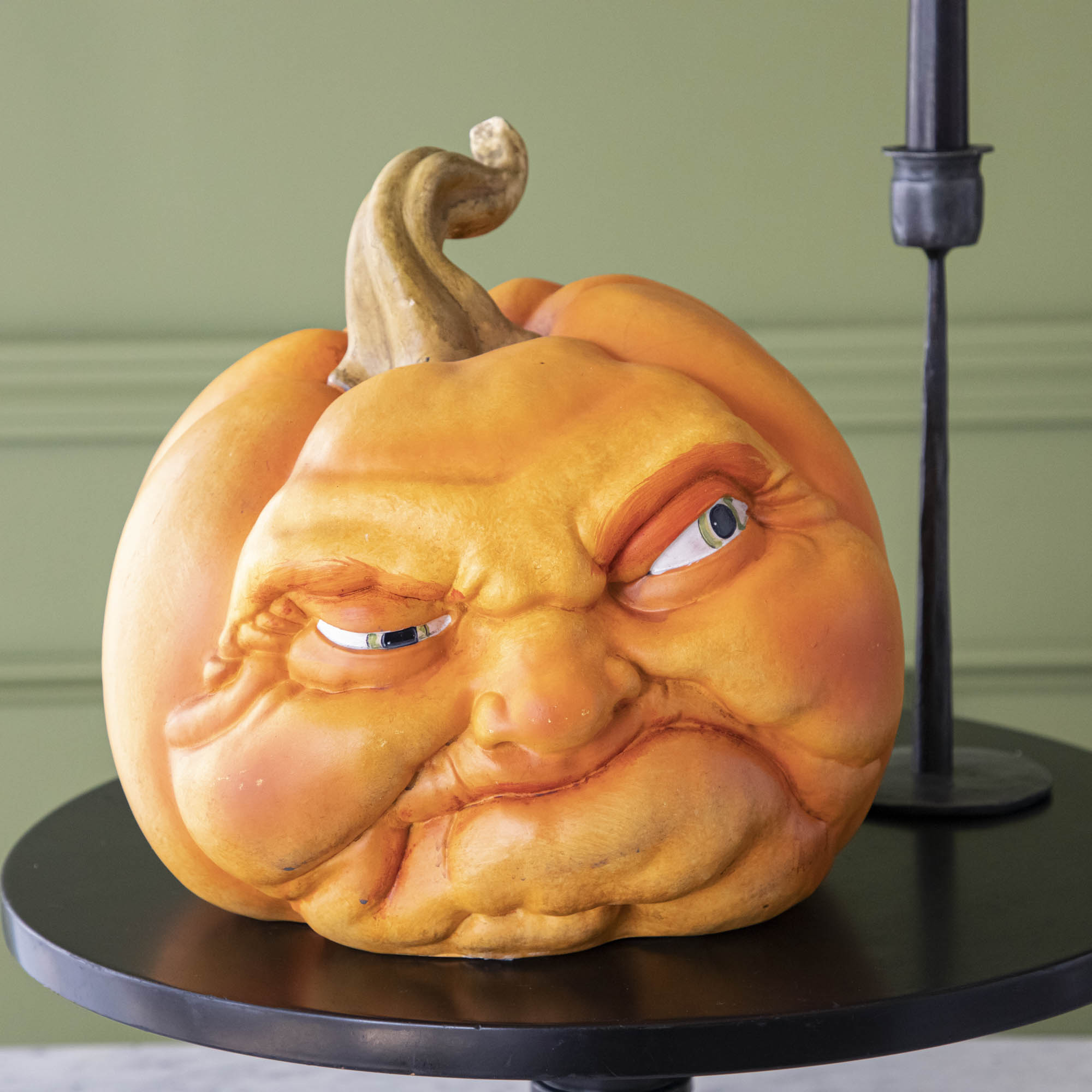 A close-up view of a pumpkin making a mean face on top of a black stand.