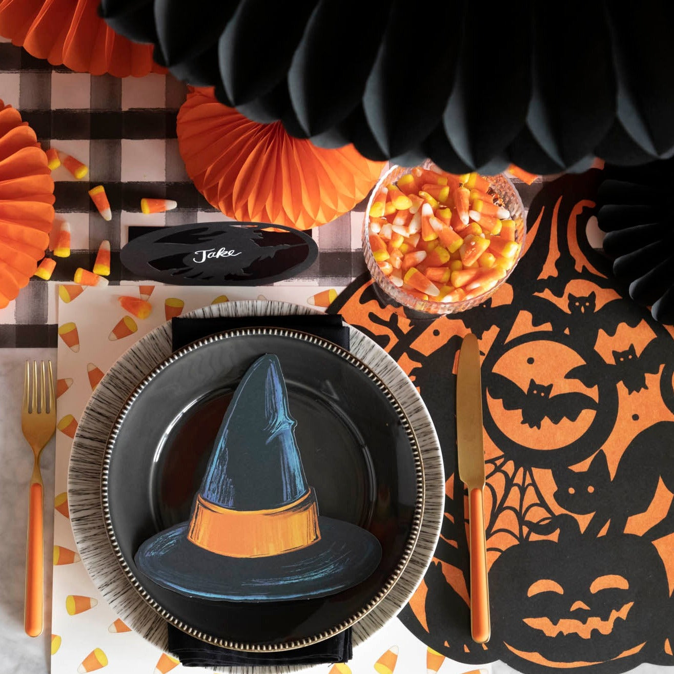 A die-cut black witch hat with an orange band, on a Halloween themed tablescape.