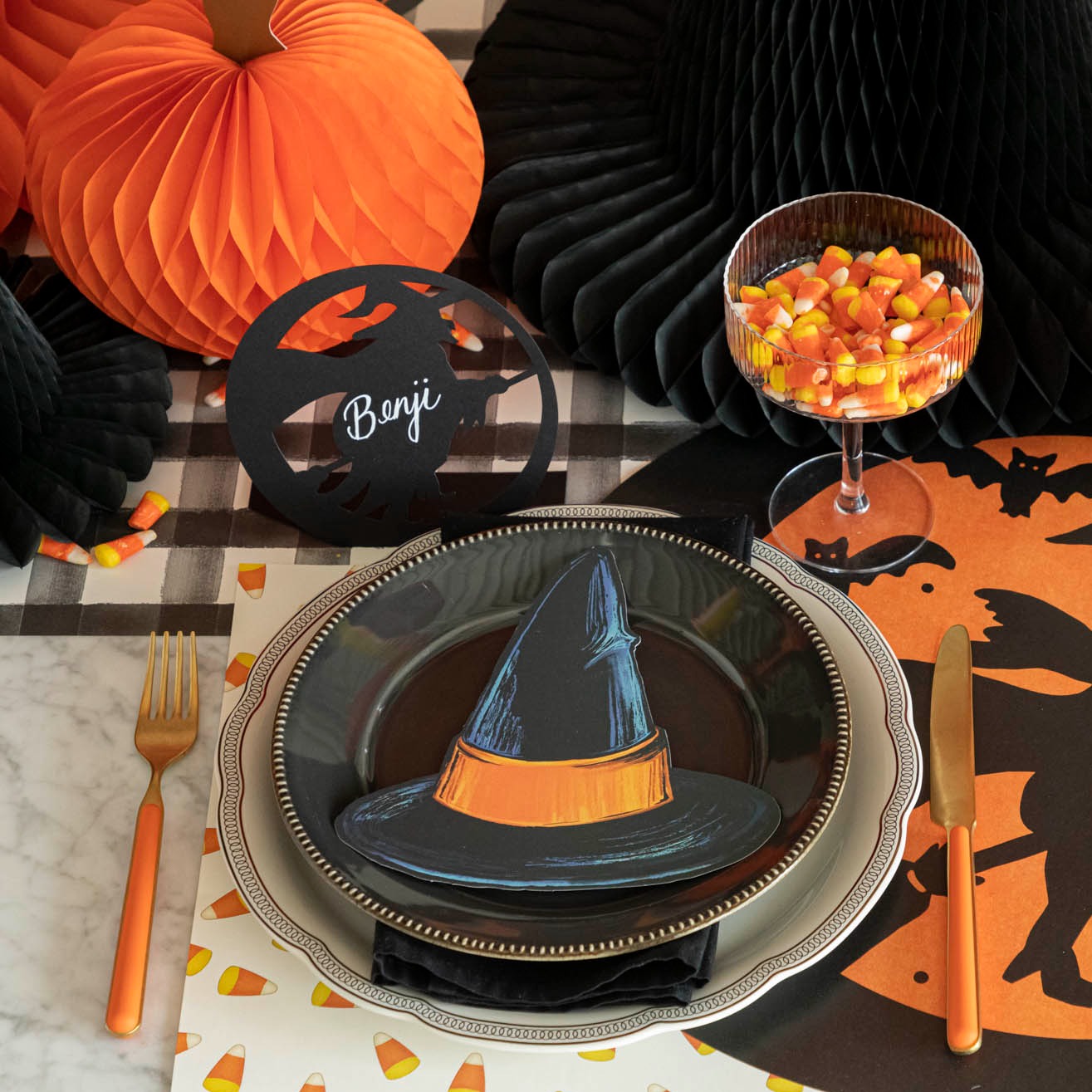 A Halloween themed table setting with orange, black and yellow colors.