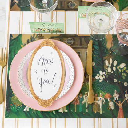 The Antique Gold Frame Table Card with &quot;Cheers to you!&quot; written on it, resting on a dinner plate on an elegant table setting.