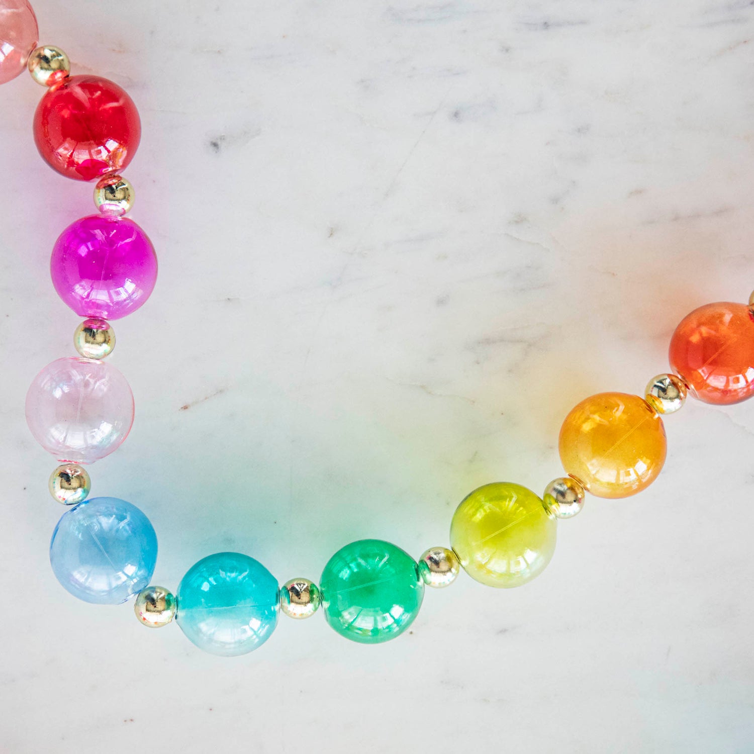 A close up of the colorful Blown Glass Rainbow Garland on a marble table.