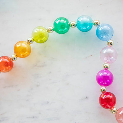 A close up of the colorful Blown Glass Rainbow Garland on a marble table.