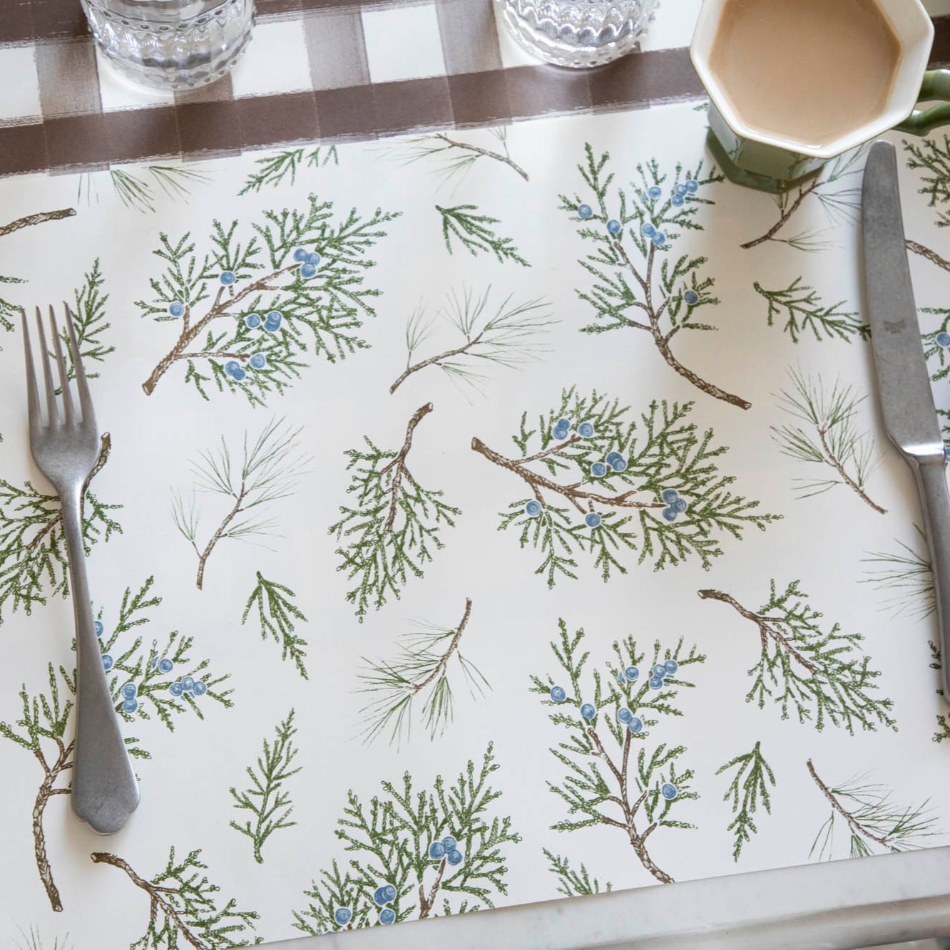 The Juniper Sprigs Placemat with silverware on top and a Brown Painted Check Runner underneath.