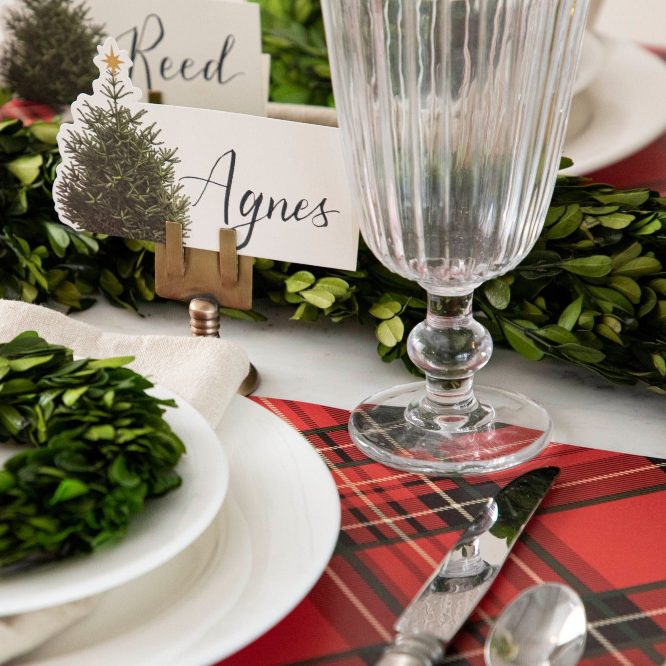 A MISPRINT Red Plaid Placemat in a red plaid fabric with black and white squares, perfect for bringing the Christmas spirit to any holiday table. (Brand: Hester &amp; Cook)