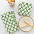 Green Lattice Napkins on a marble table next to small breadsticks on a plate and in a cup.