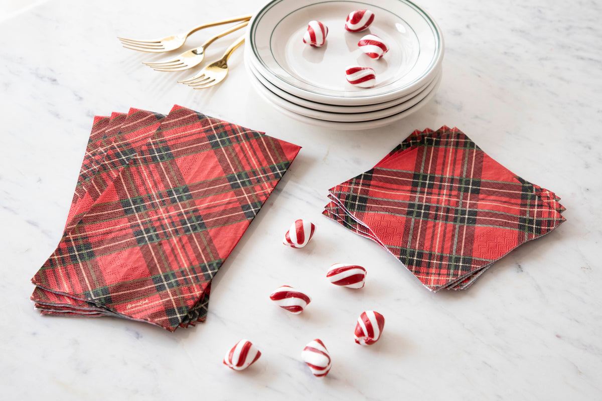 Two stacks of Red Plaid Napkins, one of Guest and one of Cocktail Napkins, on a white table with dessert plates and peppermints.