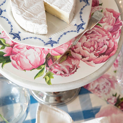 Peony Serving Paper on a cake stand under a plate of cheese, on an elegant table setting.