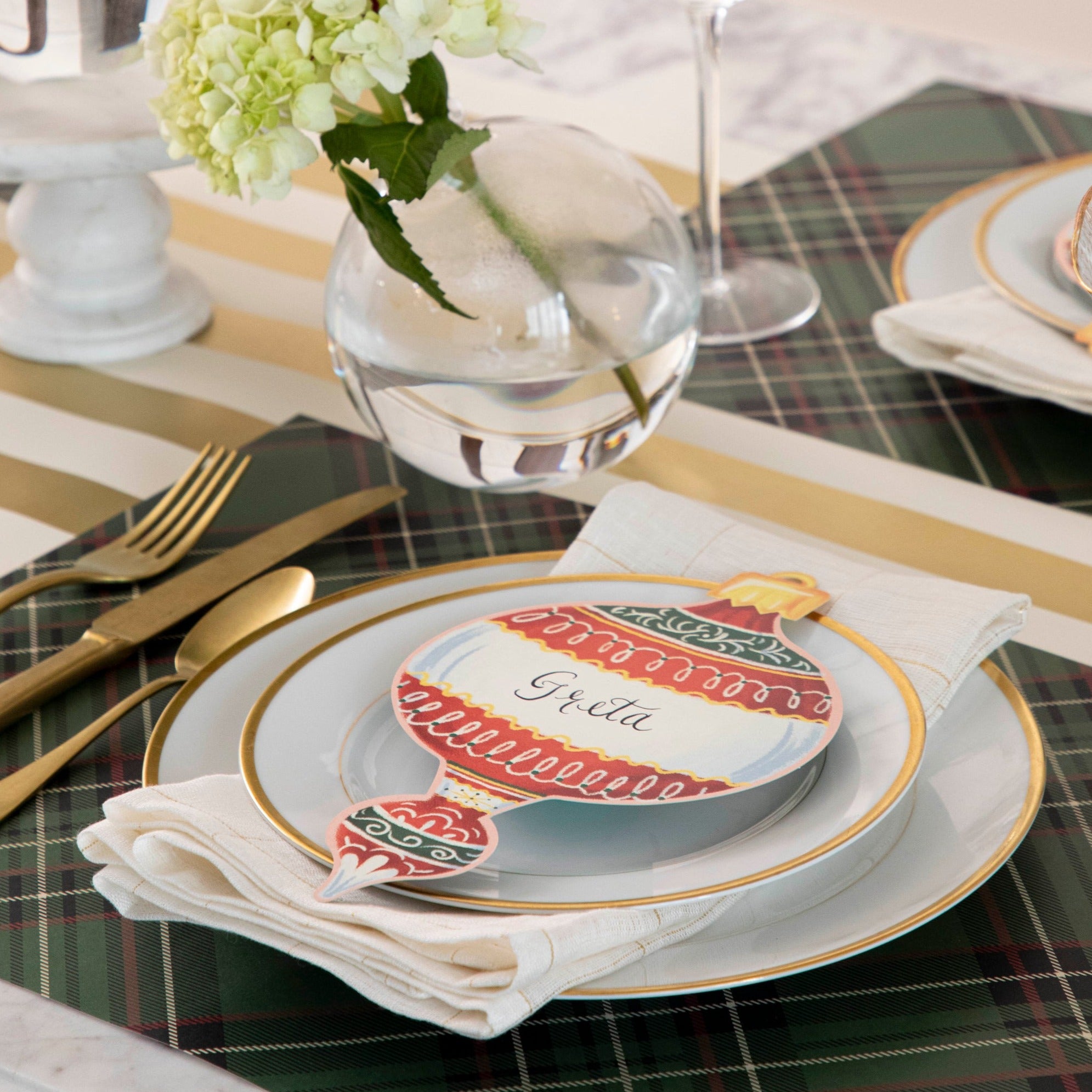 An elegant holiday place setting featuring an Ornaments Table Accent resting on the plate.