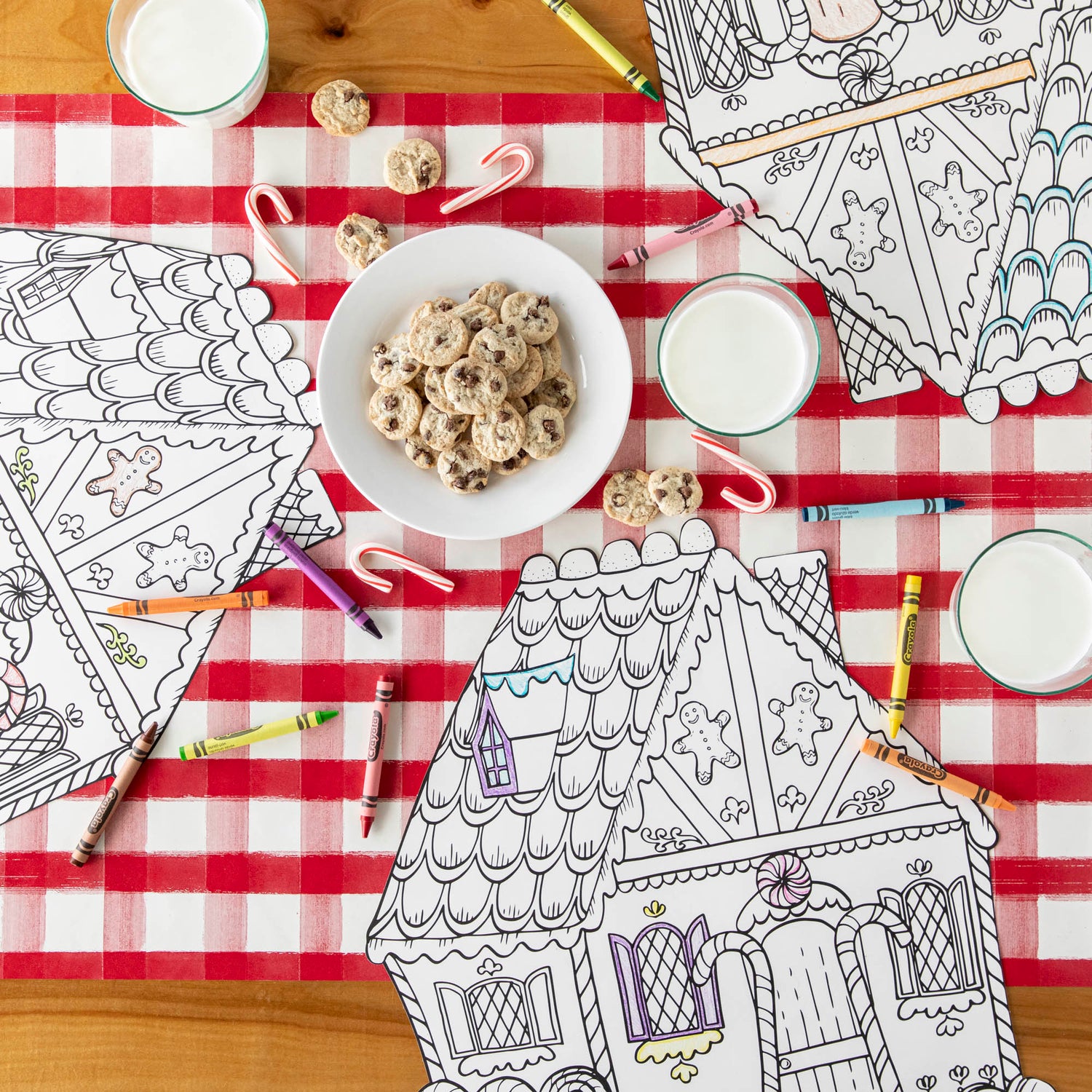 The Red Painted Check Runner under the Die-cut Coloring Gingerbread House, a plate of cookies, and crayons and candy canes scattered.