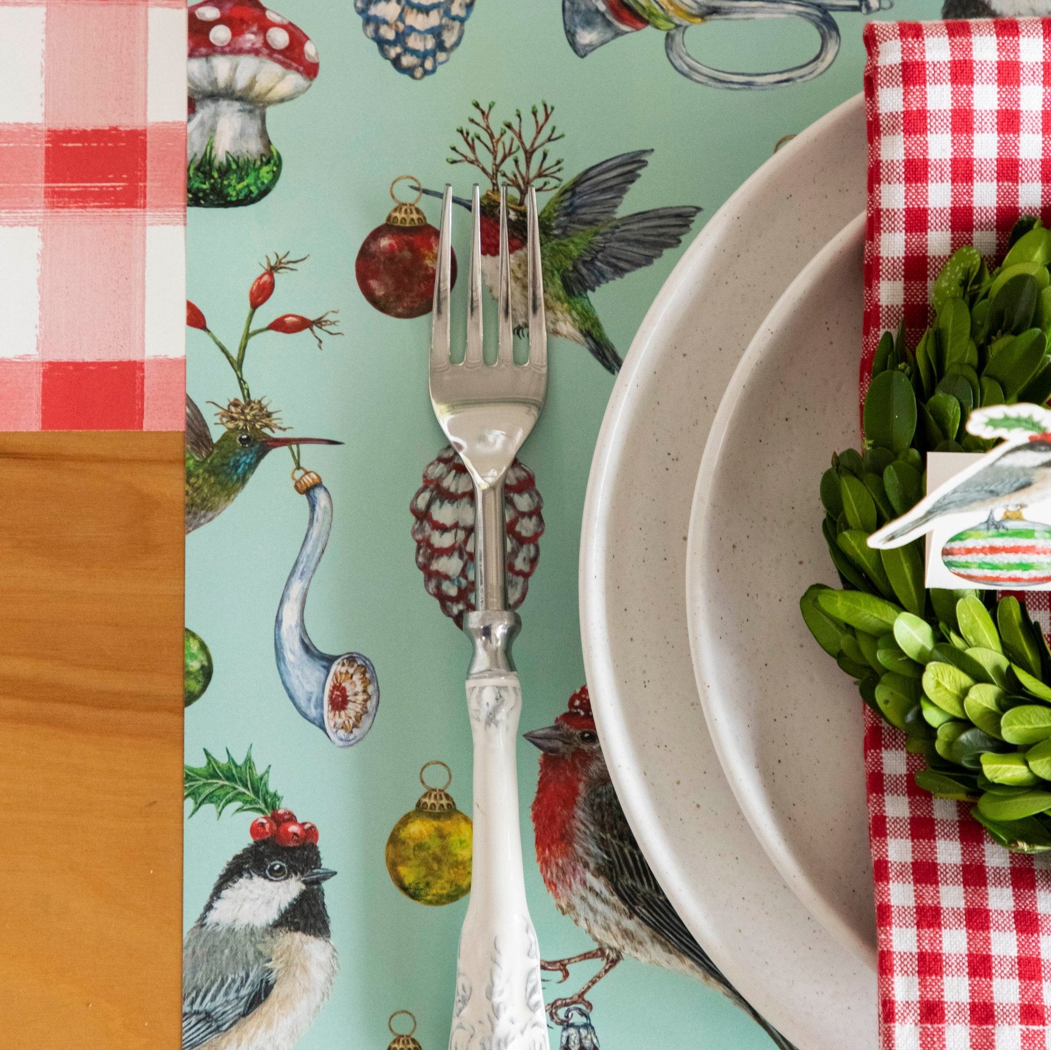 The Baubles and Birds Placemat on the Red Painted Check Runner, with a decorative fork on top.