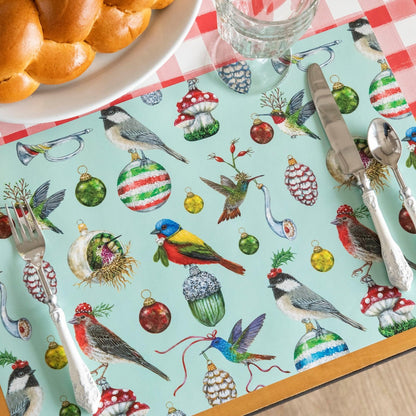 The Baubles and Birds Placemat with elegant silverware on top, a plate of bread next to it and Red Painted Check Runner underneath.